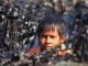A young boy looks tries to clean up the oil spill. Photo: BBC