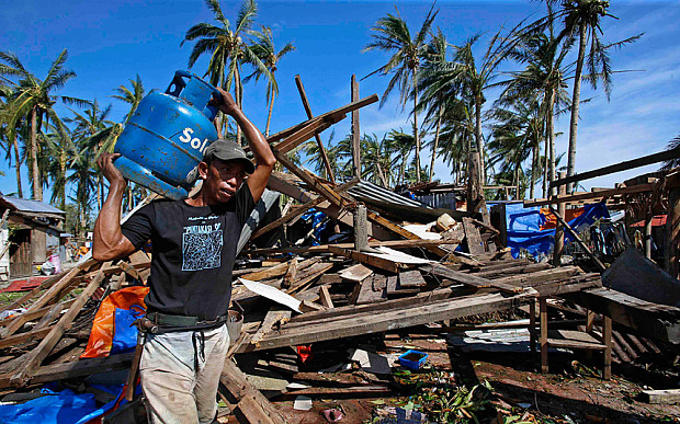 A typhoon victim carries a gas tank for cooking past a house destroyed by Typhoon Hagupit in Borongan city, Samar Photo: ERIK DE CASTRO/REUTERS